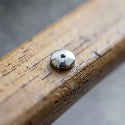 Macro 2:3 of a single rivet pin polished flush against a wooden handle