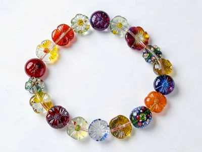 Millefiori bead necklace on white surface — beads of varying flower density