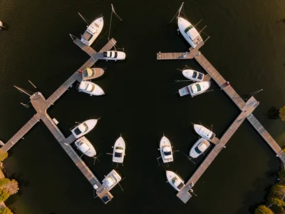 A marina from above, boats in slips creating white shapes against dark water, do
