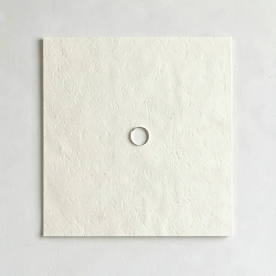 quotecard with warm cream paper texture and a small open-circle mark, no text