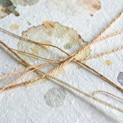 Fiber-warp running across handmade paper as warm threads bend under the weight o