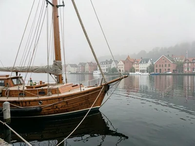Comfortable grey harbor light in Gothenburg, Sweden, the bow of a wooden sailboa