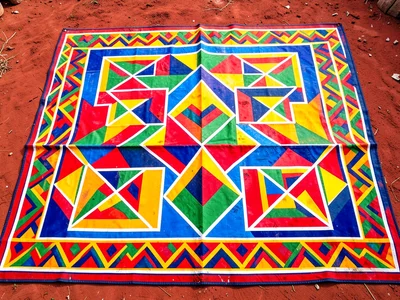 Ceremonial blanket with geometric border spread on red soil