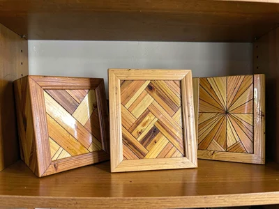 A collection of straw marquetry objects on a shelf — box, frame, and small panel