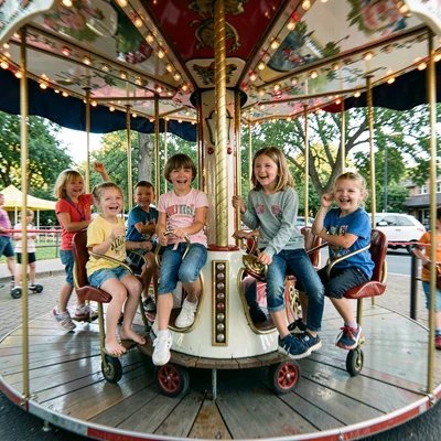 Kids on a spinning playground carousel, their joy centrifuged