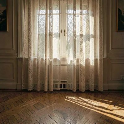 Atmospheric interior of lace curtains catching late sun, dappled light falling o