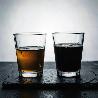 Two glasses clinking on a slate surface with lightbox-soft backlight