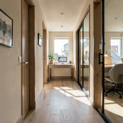 Vertical sunlit hallway leading to a glass-walled writing room