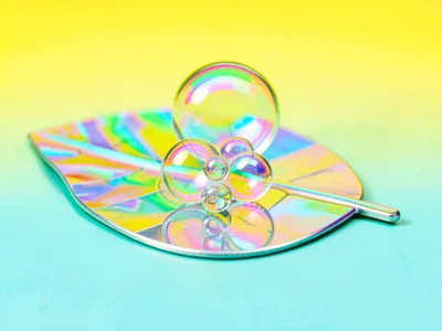 Tiny bubble cluster perched on a leaf-shaped chrome disc against a banana-yellow