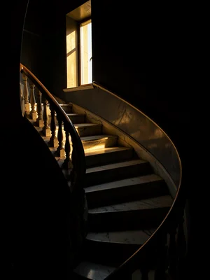 Marble staircase spiraling up from absolute darkness, a high window throwing a l