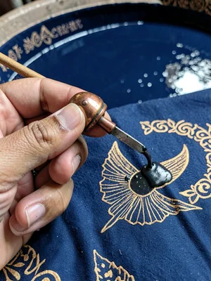 A hand holding a small copper cap tool, wax reservoir visible in the handle