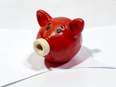Wibbly chunky clay piggy whistle in cherry red with stubby cream-toned mouthpiec