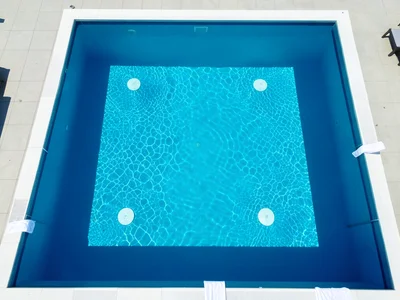 A hotel rooftop infinity pool from above, the pool edge creating a hard line whe