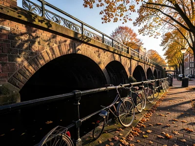 Stone bridge over a canal in Amsterdam, bicycles parked along the railing, autum