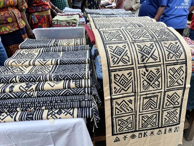 Market stall — lengths of Adinkra cloth in folded display, unrolled sample besid