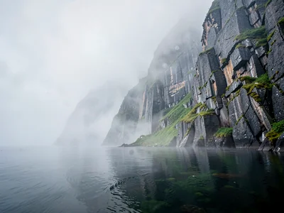 Rock face emerging from mist at water level