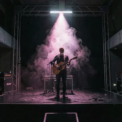 3am-shift nocturnal photo of a lone musician on stage under a single magenta was