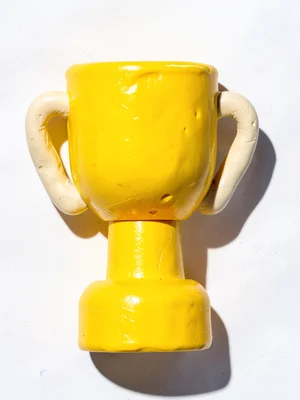 Polished chunky clay trophy in primary yellow with stubby cream-toned handles an
