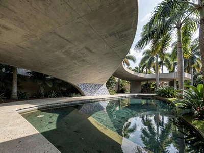Curved concrete canopy sweeping over a shallow reflecting pool edged with royal 
