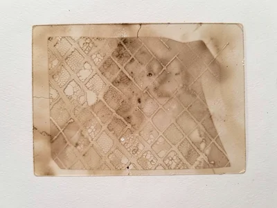 Ghost pull of a monoprint featuring pressed lace texture, faint diamond pattern 