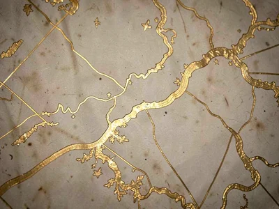 An old map detail with rivers and coastlines traced in gold over aged paper
