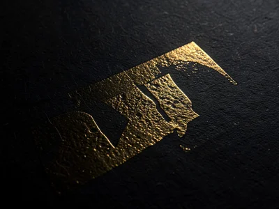 Gold foil stamp on black paper macro, metallic surface with visible carrier film