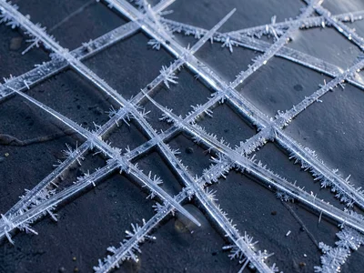 Ice needles crossing in geometric pattern on still water