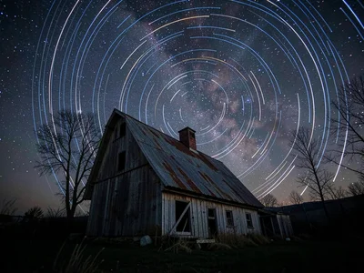 A 4-hour exposure of star trails above an abandoned barn, the stars drawing circ