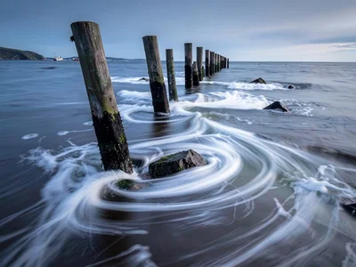 Pier pilings with water flowing past as silk