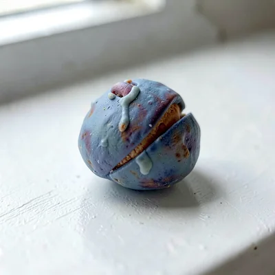 Roasted faded-blue chestnut with a thumb-pressed split along its shell and finge