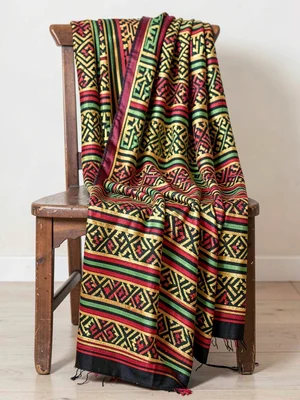 Ceremonial kente cloth draped over a wooden chair — pattern cascading in folds