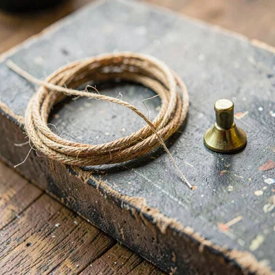 Worn-material closeup of a coiled gut string and a brass tuning peg on a chalky