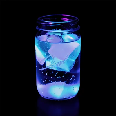 A jar of tonic water glowing blue-white under UV from its quinine content, again