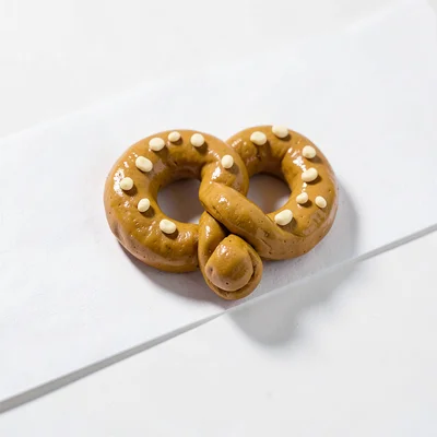 Crispy chunky clay pretzel in tan tone with stubby cream-toned salt grains and a