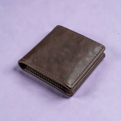 folded leather card wallet in deep cognac at three-quarter angle on a soft lilac