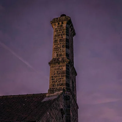 Vertical atmospheric story of a historic chimney stack at dusk against deep purp