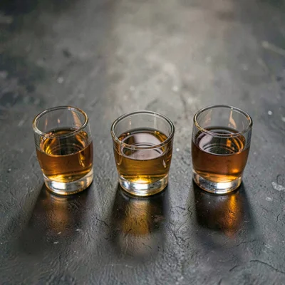 Moody composition of three small tasting glasses lined up, single overhead