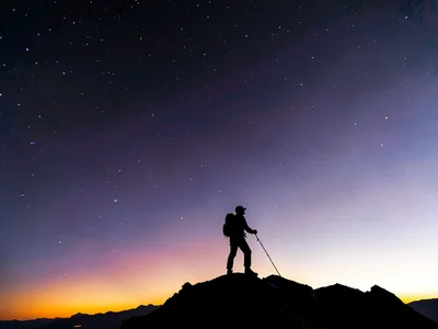 Single climber silhouette against the color zones of thinning atmosphere