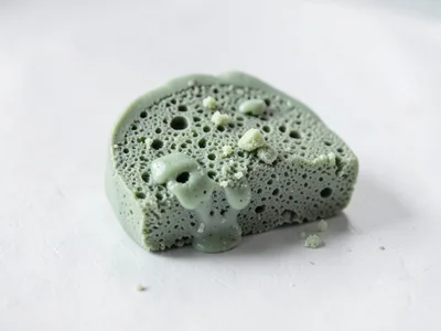 Soaked sage-green sponge cake slice with thumb-pressed crumbs and fingernail-pre