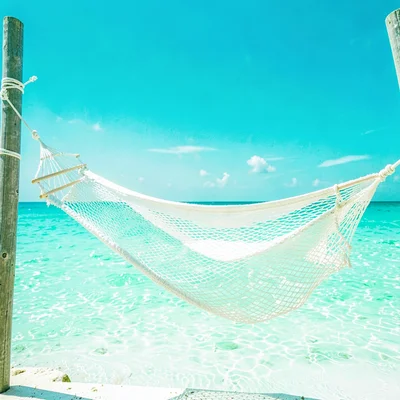 Expansive turquoise negative space, bleached whites, A hammock strung between tw