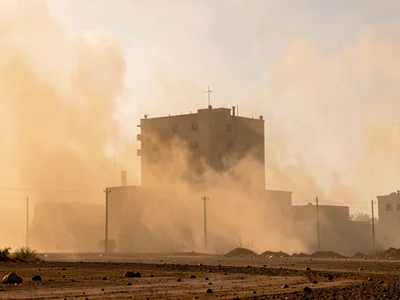Building silhouette emerging from dense Harmattan dust at noon