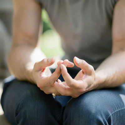 Close-up of hands in lotus mudra resting on knees, soft natural light, peaceful 