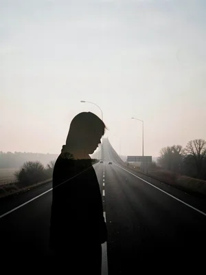Lonely figure silhouette filled with empty highway stretching to horizon, double