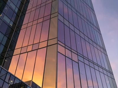 Glass tower reflecting sunset gradient orange to purple