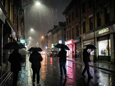 Rainy night street with umbrella silhouettes