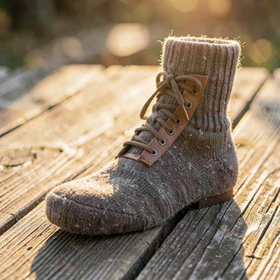 Cozy product still of a wool hiking sock and leather lace pile on weathered pine