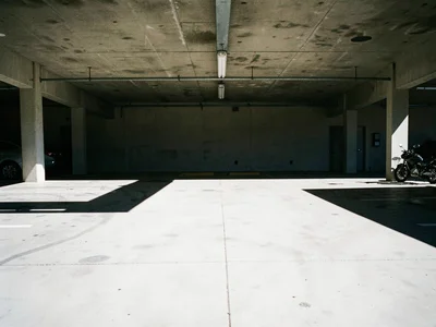 Parking lot at noon with bleached concrete and hard black shadows