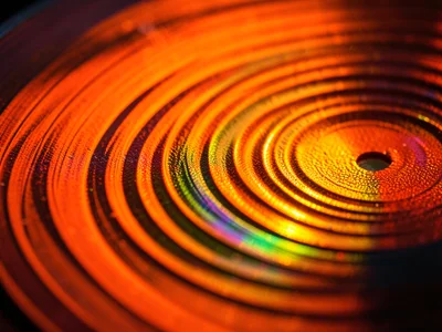 Colored vinyl record, translucent orange pressing backlit to show groove pattern