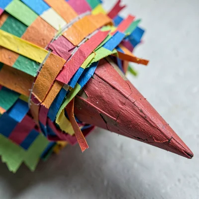 Close-up of the pointed cone end of a piñata spike — paper fringe and layered ba