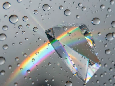 Spectral light passing through raindrops on a window, each drop acting as micro-